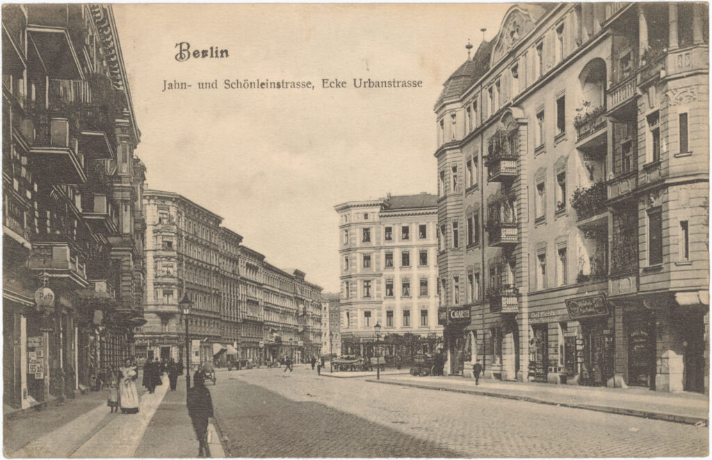 Agnes Fahrenwald, Vorsitzende des Allgemeinen Arbeiterinnen-Vereins, wohnte in der Schönleinstr. 19. Die Ansichtskarte zeigt einen Blick aus der Jahnstr. in die Schönleinstr.; die Nr. 19 ist das zweite, schmalere Haus auf der linken Seite hinter der Kreuzung. In der Schönleinstr. 17 zwei Häuser weiter hinten lebte Herr A. Riese, Vorsitzender des Vereins der Arbeiter und Arbeiterinnen der Buch-, Papier-, und Lederwarenindustrie. „Jahn- und Schönleinstr., Ecke Urbanstr.“, o.D (verschickt am 10.02.1910), SPP / FHXB 1975